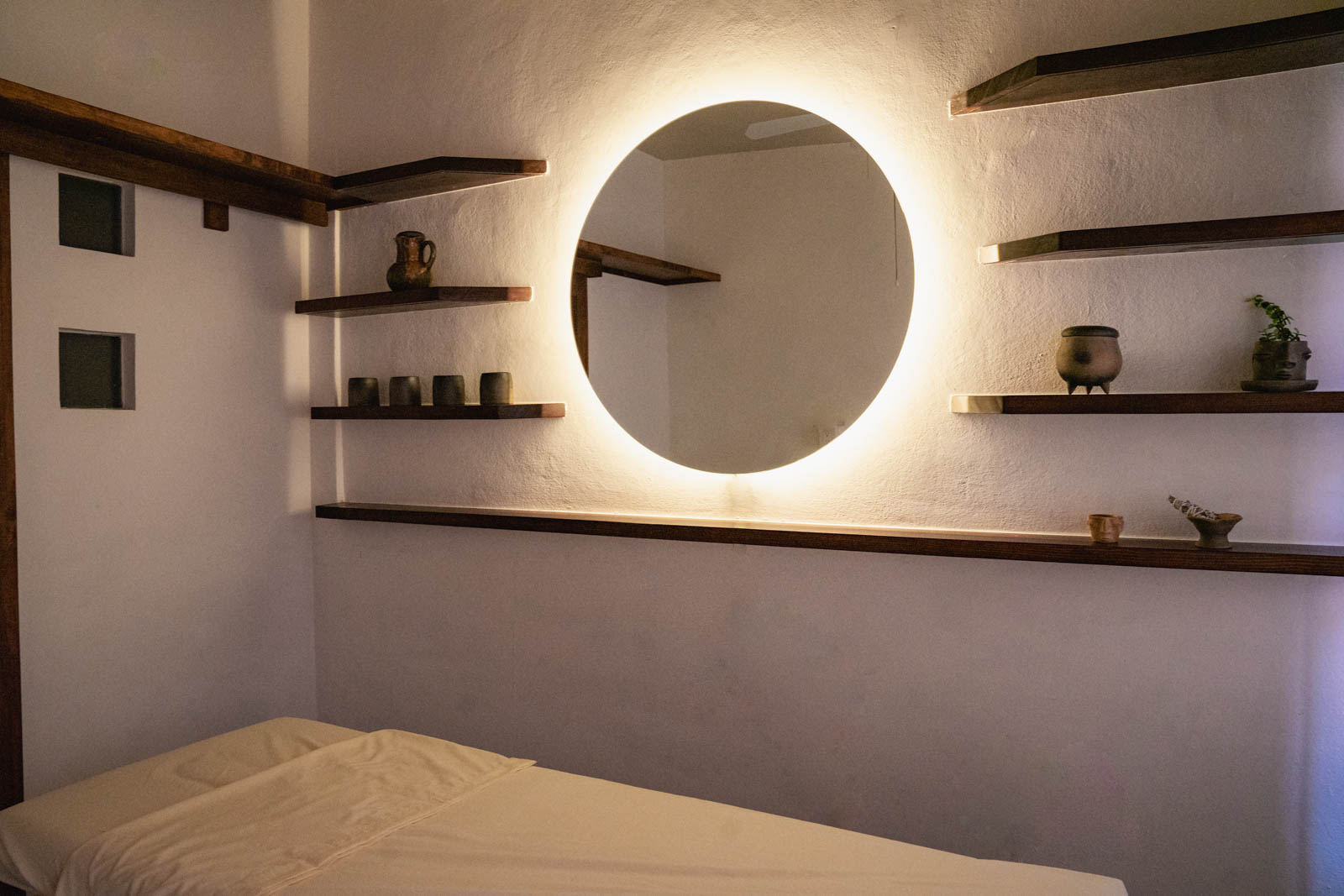Casa de Portales healing studio with a massage table and illuminated round mirror